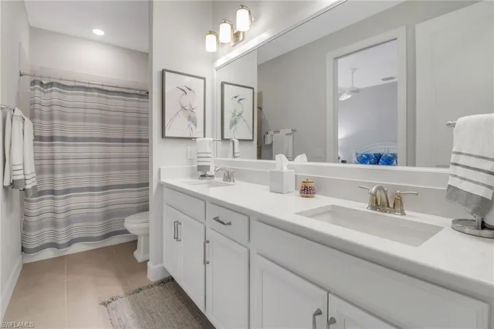 Full bath featuring ensuite bathroom, double vanity, tile patterned flooring, and a sink