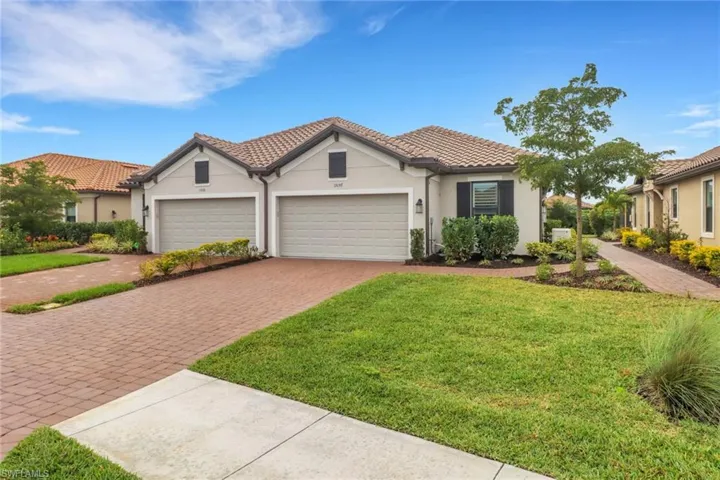 Mediterranean / spanish home with decorative driveway, stucco siding, an attached garage, a front yard, and a tiled roof