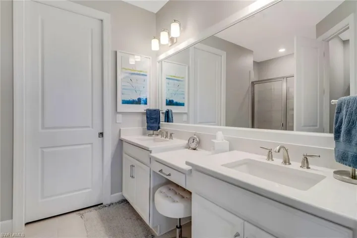 Bathroom with double vanity, tile patterned flooring, a sink, and a shower stall