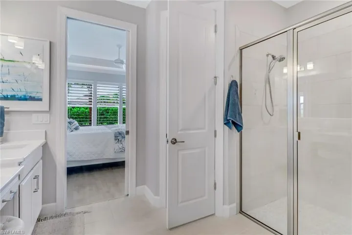 Full bath with connected bathroom, a shower stall, vanity, tile patterned flooring, and baseboards