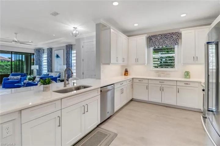 Kitchen featuring a sink, white cabinetry, open floor plan, light countertops, and dishwasher