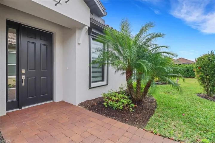 View of exterior entry with a yard and stucco siding