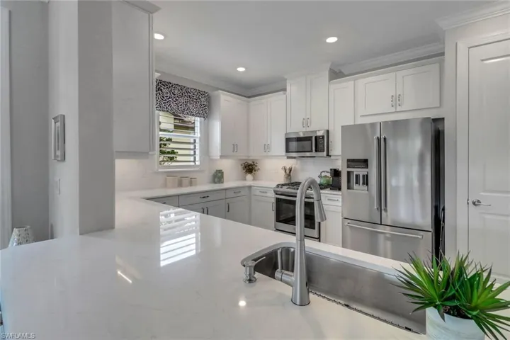 Kitchen featuring stainless steel appliances, white cabinetry, crown molding, and tasteful backsplash