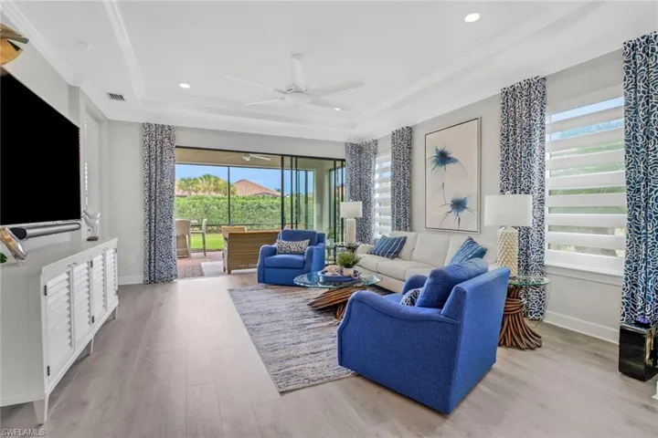 Living area featuring light wood-style flooring, a raised ceiling, visible vents, and baseboards