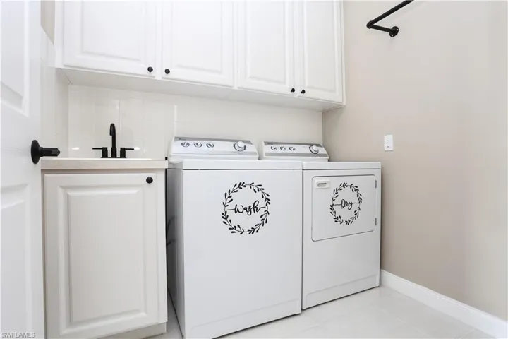 Laundry area featuring cabinet space, light tile patterned floors, and washer and dryer