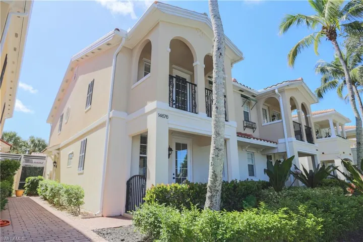 View of front of property featuring stucco siding, a balcony, and a gate