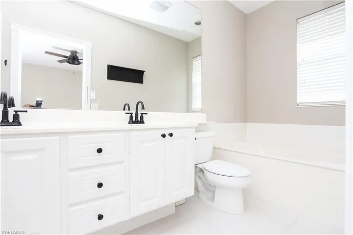 Full bath with a garden tub, double vanity, light tile patterned floors, and ceiling fan