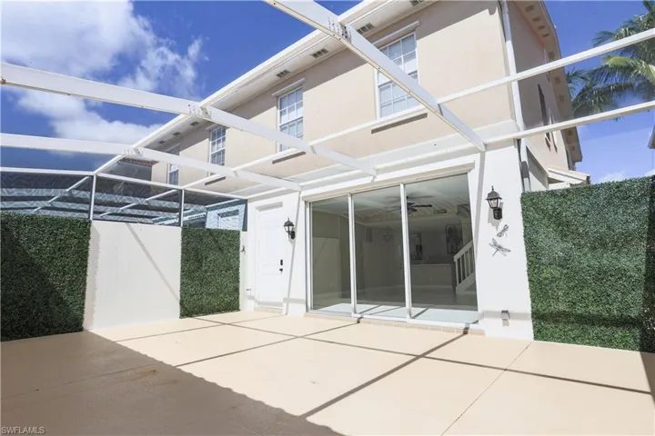 Rear view of house with a patio area, stucco siding, and glass enclosure