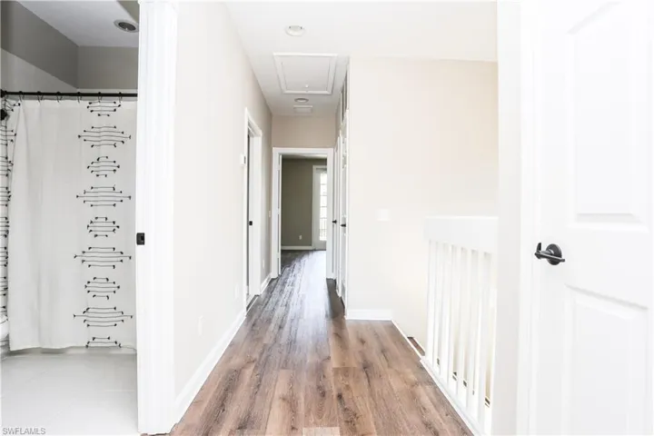 Hall featuring attic access and wood finished floors