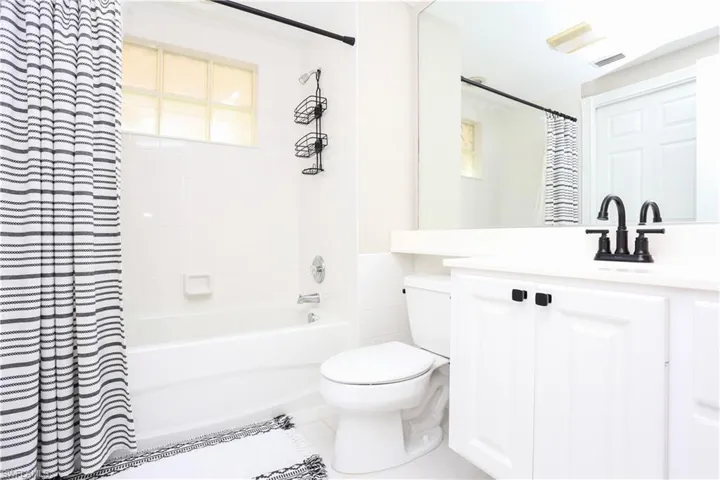 Full bathroom with shower / bathtub combination with curtain, vanity, and tile patterned floors