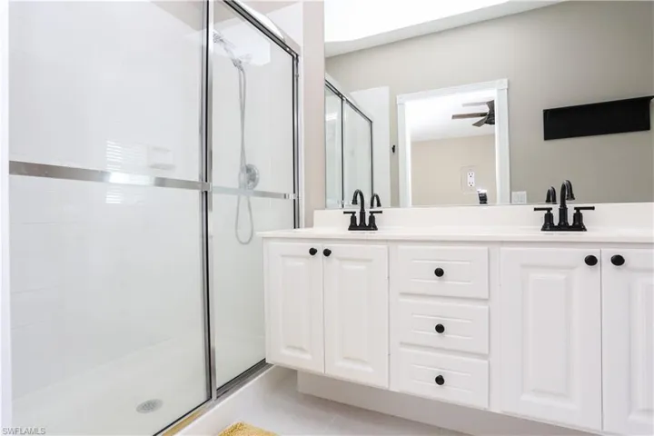 Full bathroom featuring a shower stall, double vanity, and light tile patterned floors