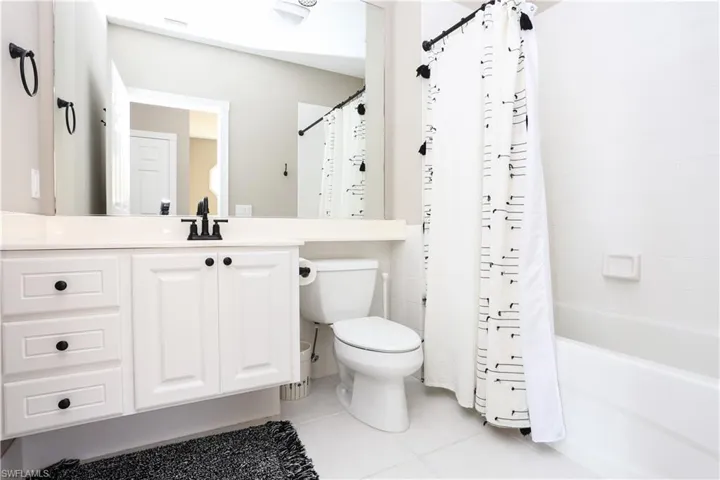 Bathroom with light tile patterned flooring, shower / bath combo, and vanity