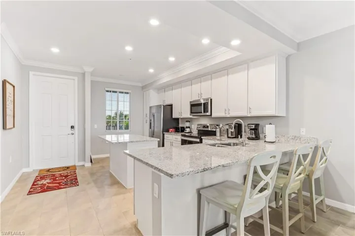Kitchen with crown molding, stainless steel appliances, a breakfast bar area, kitchen peninsula, and sink