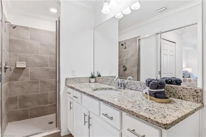 Bathroom with a shower with shower door, crown molding, and vanity