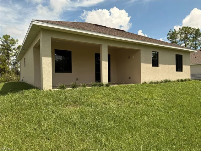 Stucco exterior with multiple windows, recessed covered patio, and shingle roof