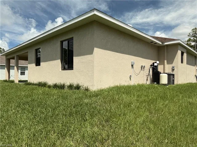 Stucco exterior with covered patio, multiple windows, and a shingle roof