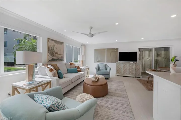 Living room with plenty of natural light, light wood-type flooring, ceiling fan, and ornamental molding