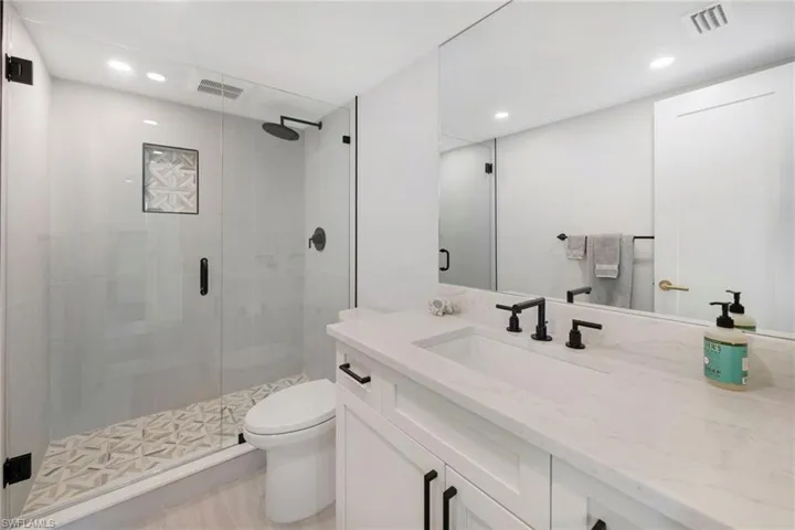 Bathroom with vanity, toilet, and a shower with door