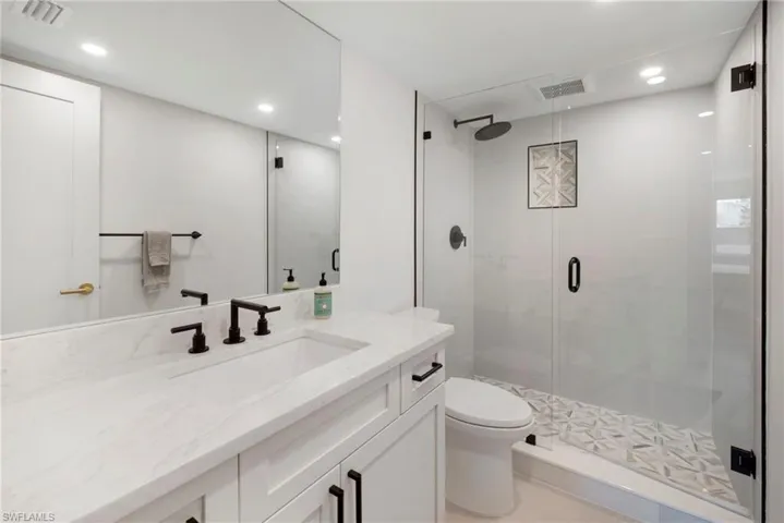 Bathroom featuring vanity, an enclosed shower, and toilet