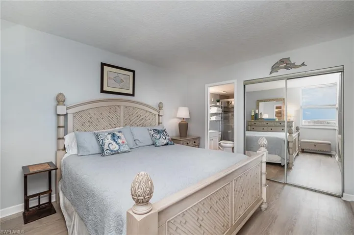 Bedroom with light wood finished floors, a closet, a textured ceiling, and ensuite bathroom