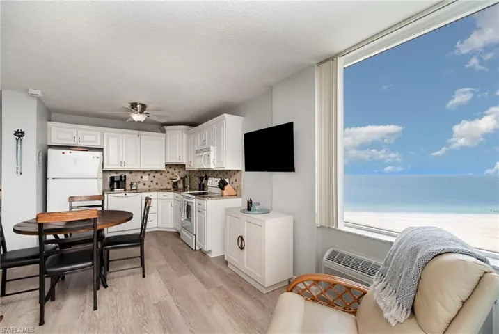 Kitchen with white appliances, white cabinets, tasteful backsplash, light wood-style floors, and a textured ceiling