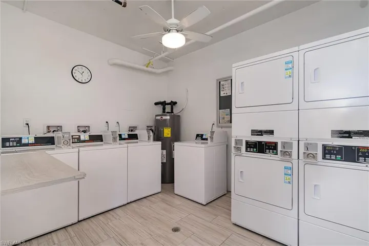 Community laundry with water heater, stacked washing machine and dryer, washer and clothes dryer, and a ceiling fan