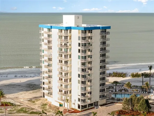 View of apartment building / complex featuring view of water and beach