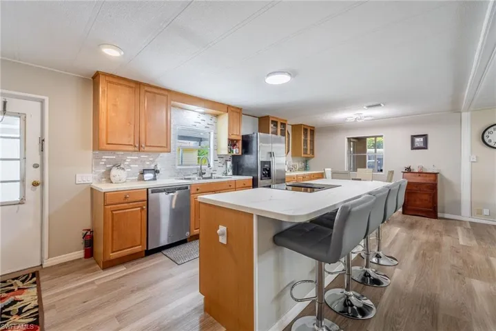 Kitchen featuring a breakfast bar, a center island, decorative backsplash, stainless steel appliances, and a sink