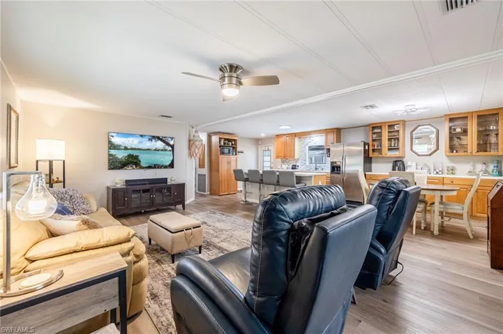 Living room featuring light wood-type flooring, ceiling fan, and visible vents