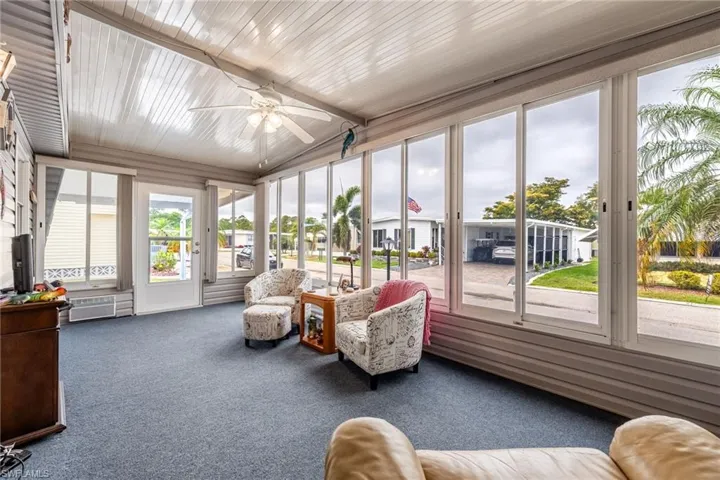 Sunroom featuring a ceiling fan and carpet floors
