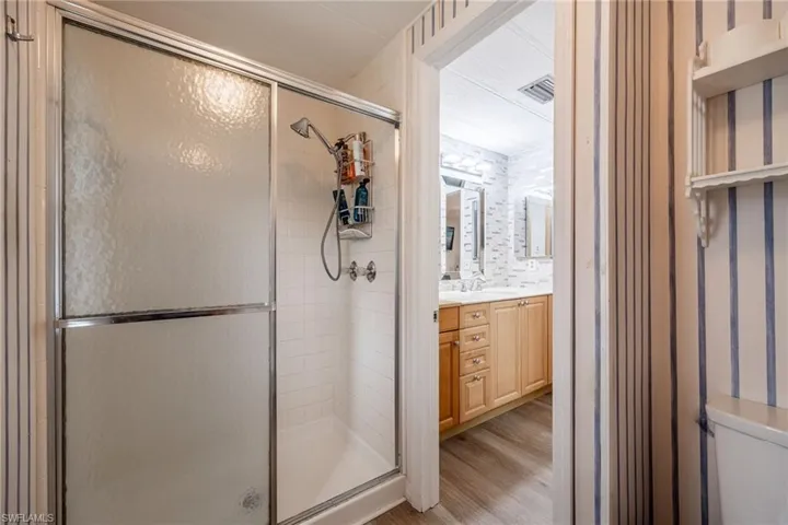 Full bath with visible vents, a shower stall, vanity, and wood finished floors