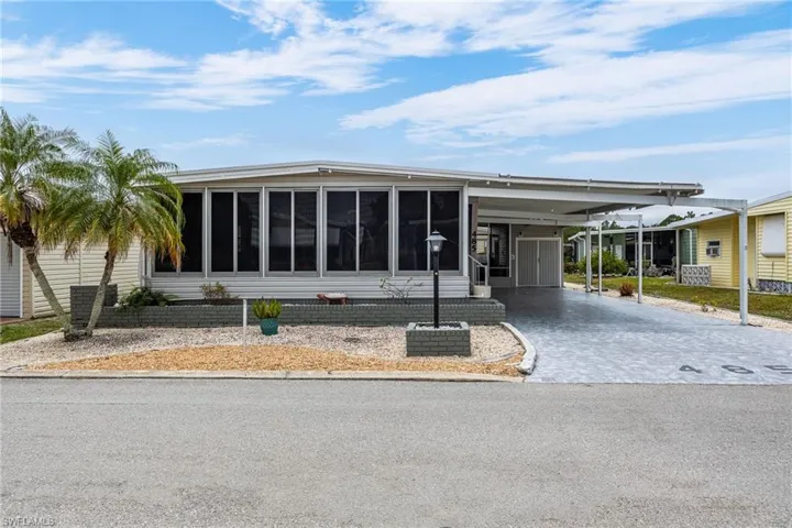 Manufactured / mobile home featuring a carport, driveway, and a sunroom