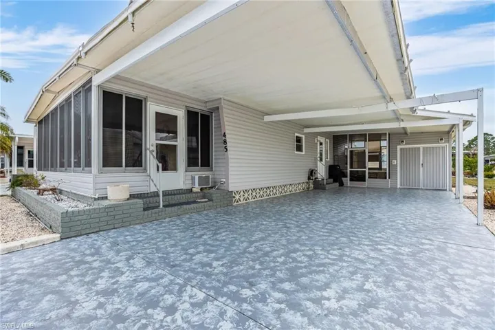 View of front of house featuring a carport, entry steps, a sunroom, and driveway