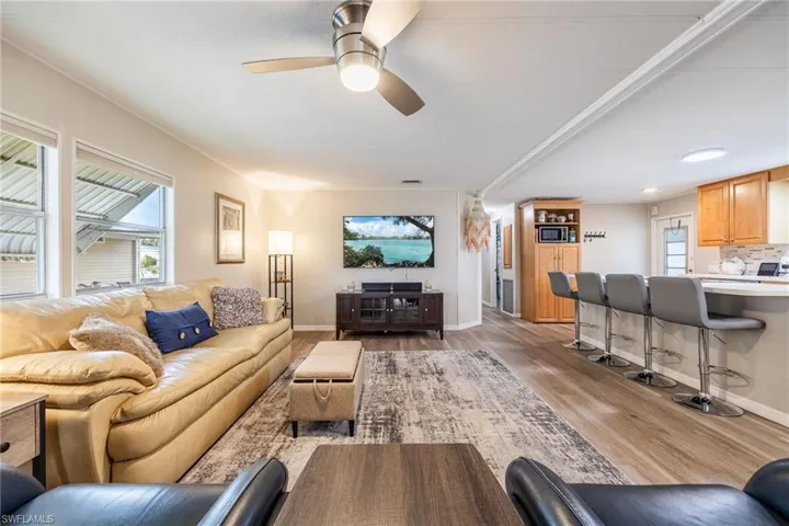 Living area with light wood-style floors, ceiling fan, and baseboards