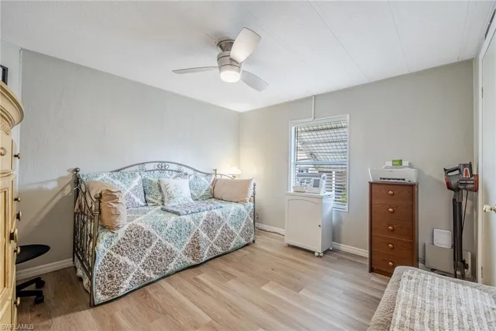 Bedroom with light wood finished floors, baseboards, and a ceiling fan