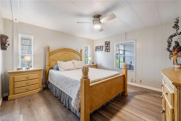 Bedroom featuring ceiling fan, multiple windows, baseboards, and wood finished floors