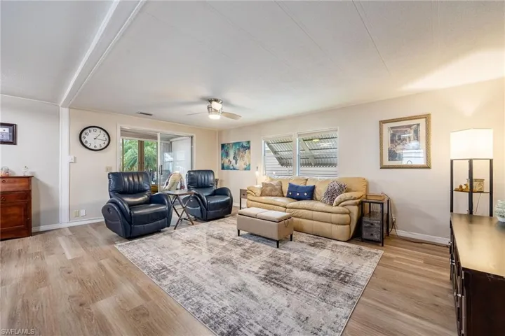 Living area with light wood-style floors, baseboards, a ceiling fan, and visible vents