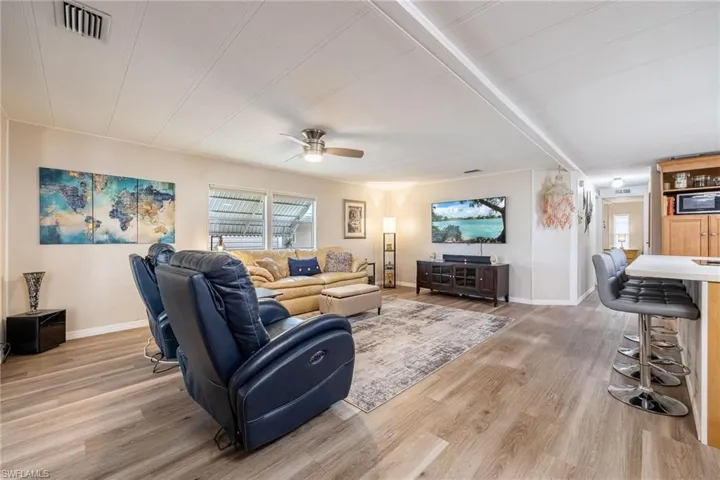 Living area featuring visible vents, baseboards, light wood finished floors, and a ceiling fan
