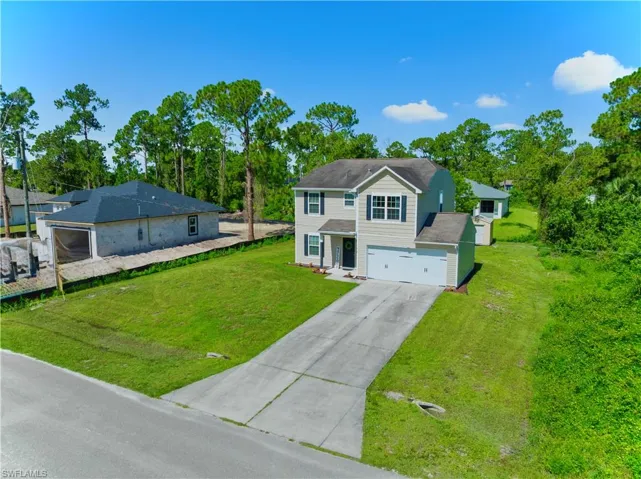 View of front of house featuring concrete driveway, an attached garage, and a front lawn