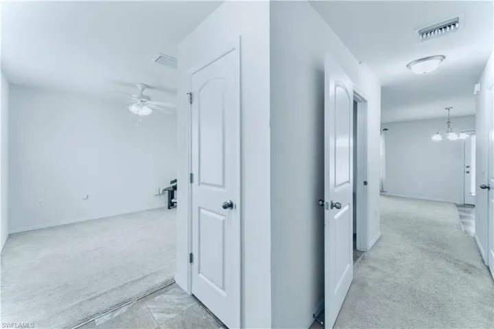 Hallway with light carpet and a chandelier