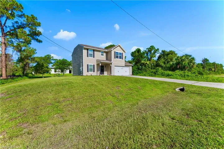 Traditional-style house with concrete driveway, an attached garage, and a front lawn