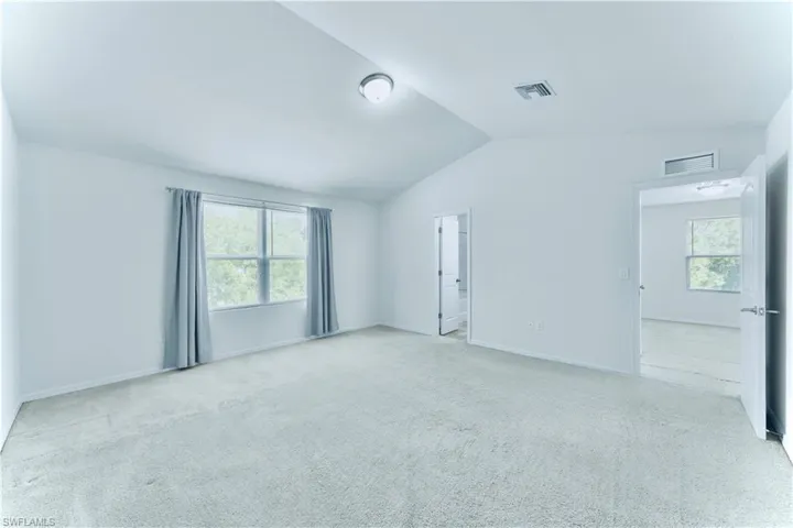 Unfurnished bedroom featuring vaulted ceiling and carpet