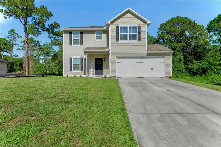 View of front of house featuring concrete driveway, a front lawn, and an attached garage