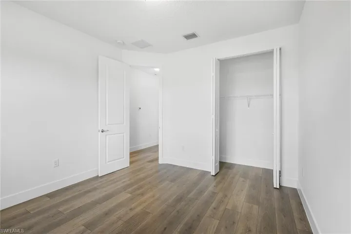 Unfurnished bedroom with dark wood-style floors and a closet