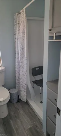 Bathroom featuring hardwood / wood-style flooring, toilet, and walk in shower