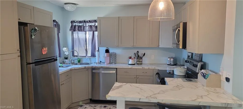 Kitchen featuring kitchen peninsula, appliances with stainless steel finishes,  and new gray cabinets