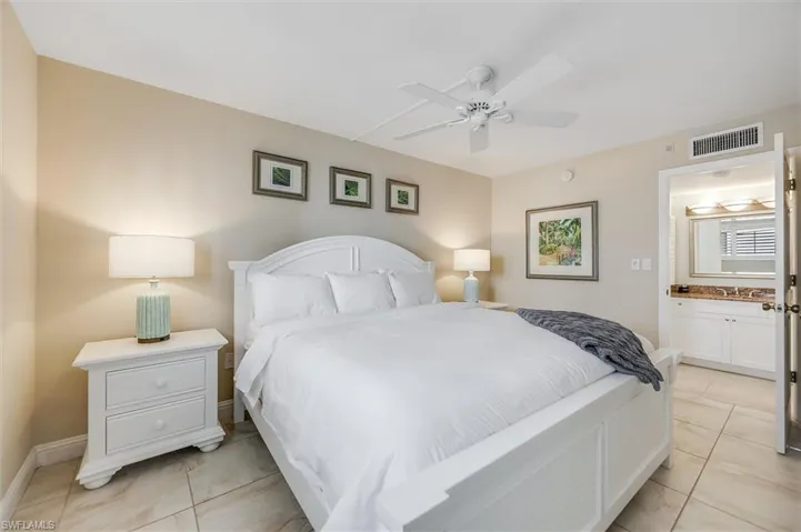 Bedroom featuring light tile patterned floors, a ceiling fan, and ensuite bathroom