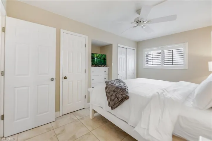 Bedroom with two closets, a ceiling fan, and light tile patterned flooring