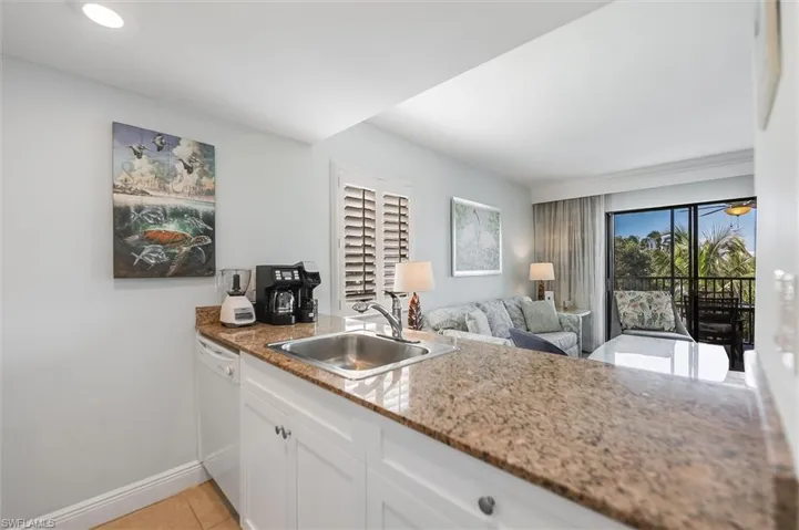 Kitchen with white cabinetry, dishwasher, light tile patterned floors, light stone counters, and open floor plan