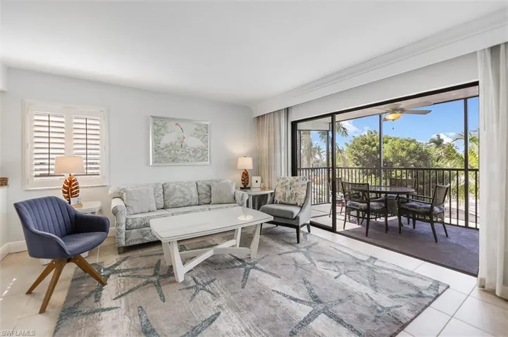Living room featuring light tile patterned floors, ceiling fan, and a sunroom